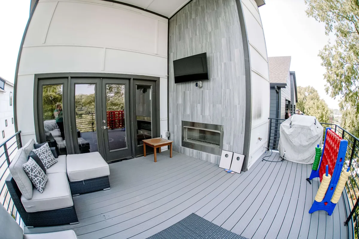 An inviting outdoor area set up for family relaxation, including a colorful play structure, fireplace, outdoor TV, and comfortable seating. The space feels lively and inclusive, suggesting a home where all family members, including pets, are welcome to gather and play.