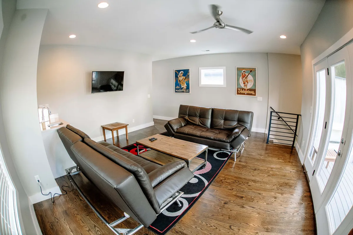 A comfortable, modern living room featuring leather sofas, a coffee table, and artwork on the walls. The arrangement promotes casual gatherings, socializing, and shared entertainment experiences.