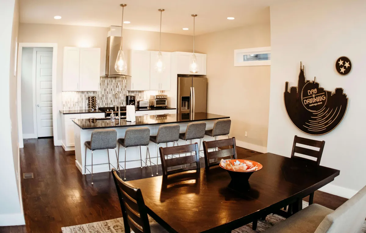 This image features an open-concept space with a kitchen island, a large dining table suitable for group meals, and eye-catching decorative wall art. The layout is bright and inviting, with ample room for cooking, serving, and gathering. The furnishings and atmosphere encourage communal activities like cooking together, group dinners, and socializing.