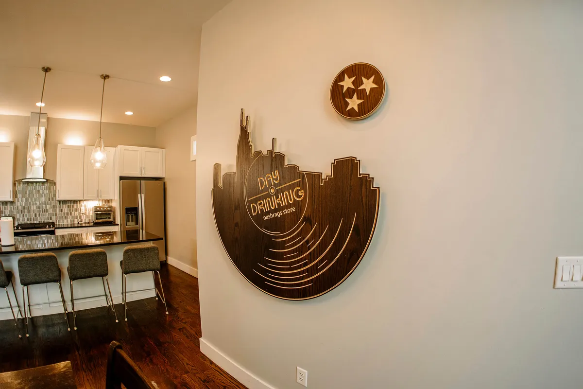 A bright, open kitchen with stylish decorative wall art, sleek countertops, and inviting bar stools, perfect for gatherings. The space exudes a casual, welcoming vibe, ideal for cooking, entertaining, and soaking in Nashville’s musical spirit.